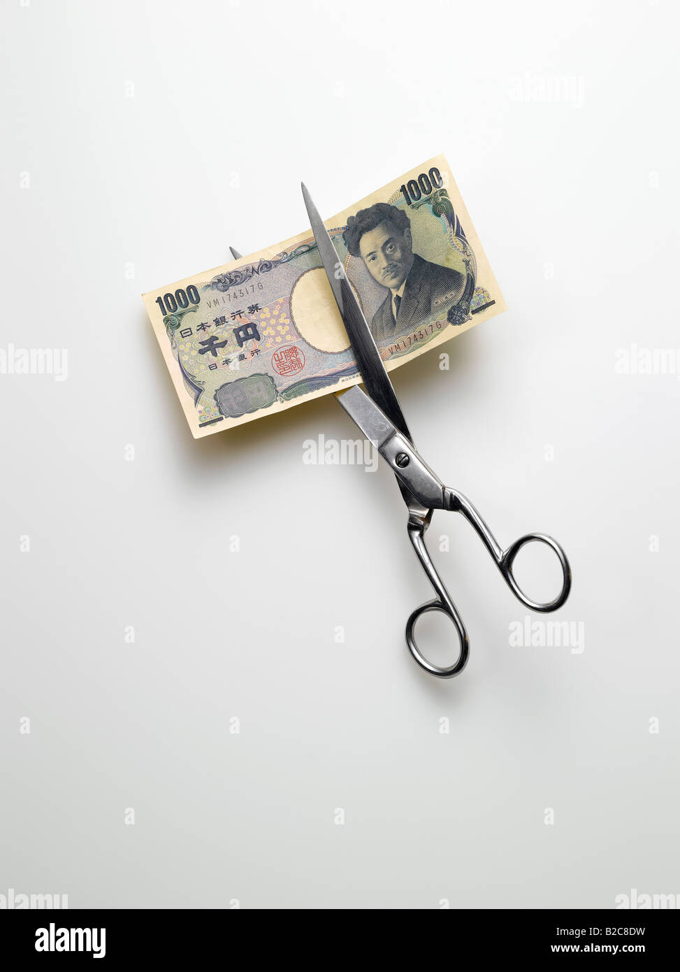 Taglio a forbice yen giapponese denaro su sfondo bianco Foto Stock