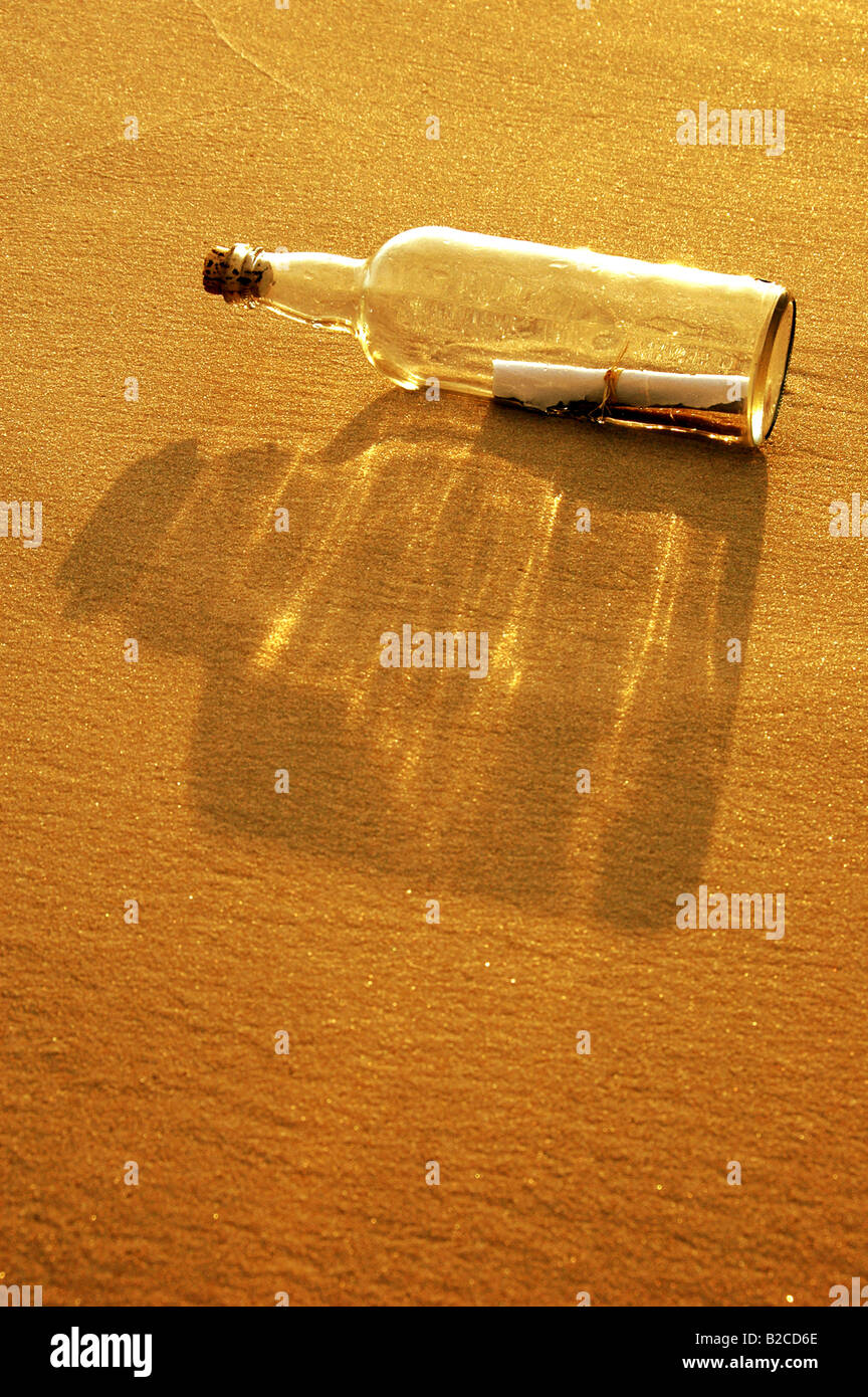 Un messaggio in bottiglia su una spiaggia di sabbia al tramonto Foto Stock