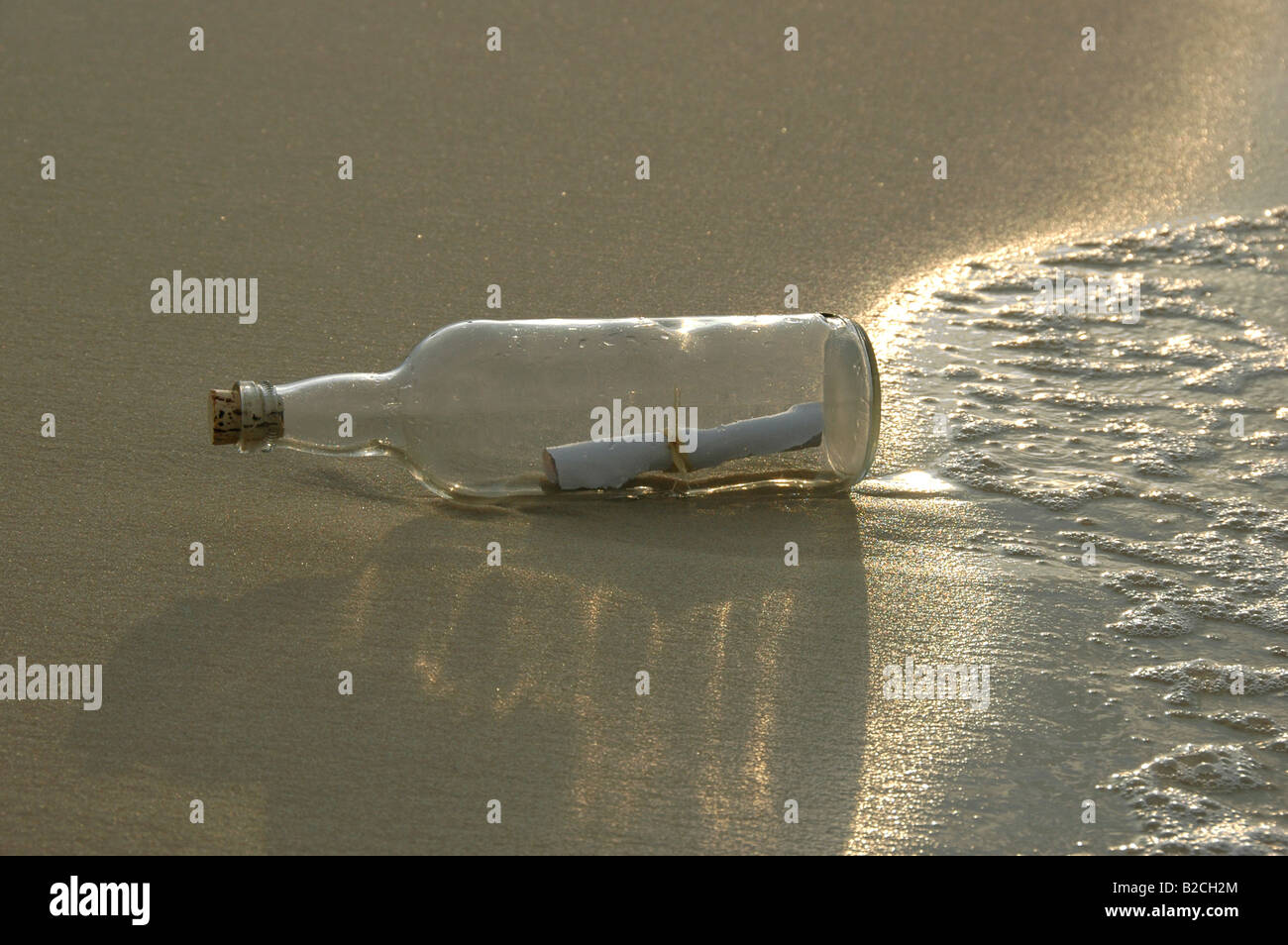 Un messaggio in bottiglia con una forte luce del sole al tramonto Foto Stock