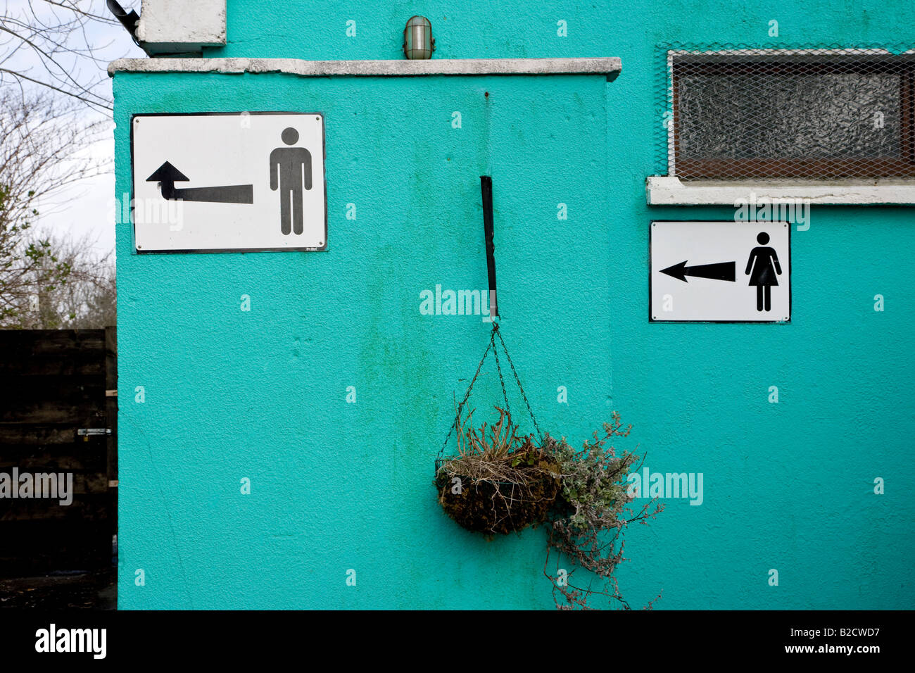 Sporco bagni pubblici, maschio e femmina, con segni e frecce, Sneem, nella contea di Kerry, Irlanda Foto Stock