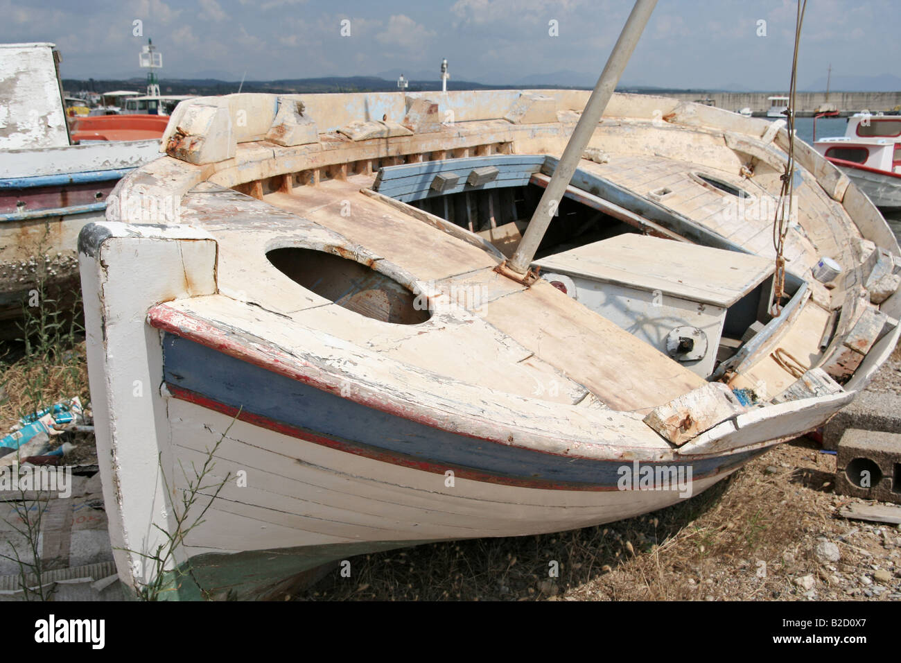 Una vecchia imbarcazione in appoggio sulla sabbia di un piccolo porto Foto Stock