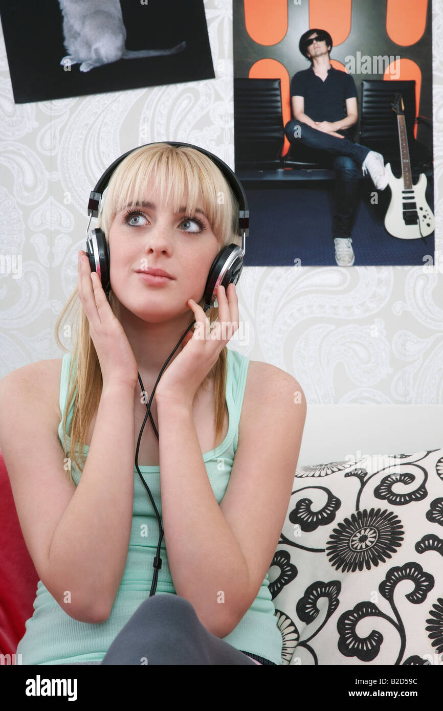 Ragazza adolescente (16-17) seduto sul letto e ascolto di musica Foto Stock