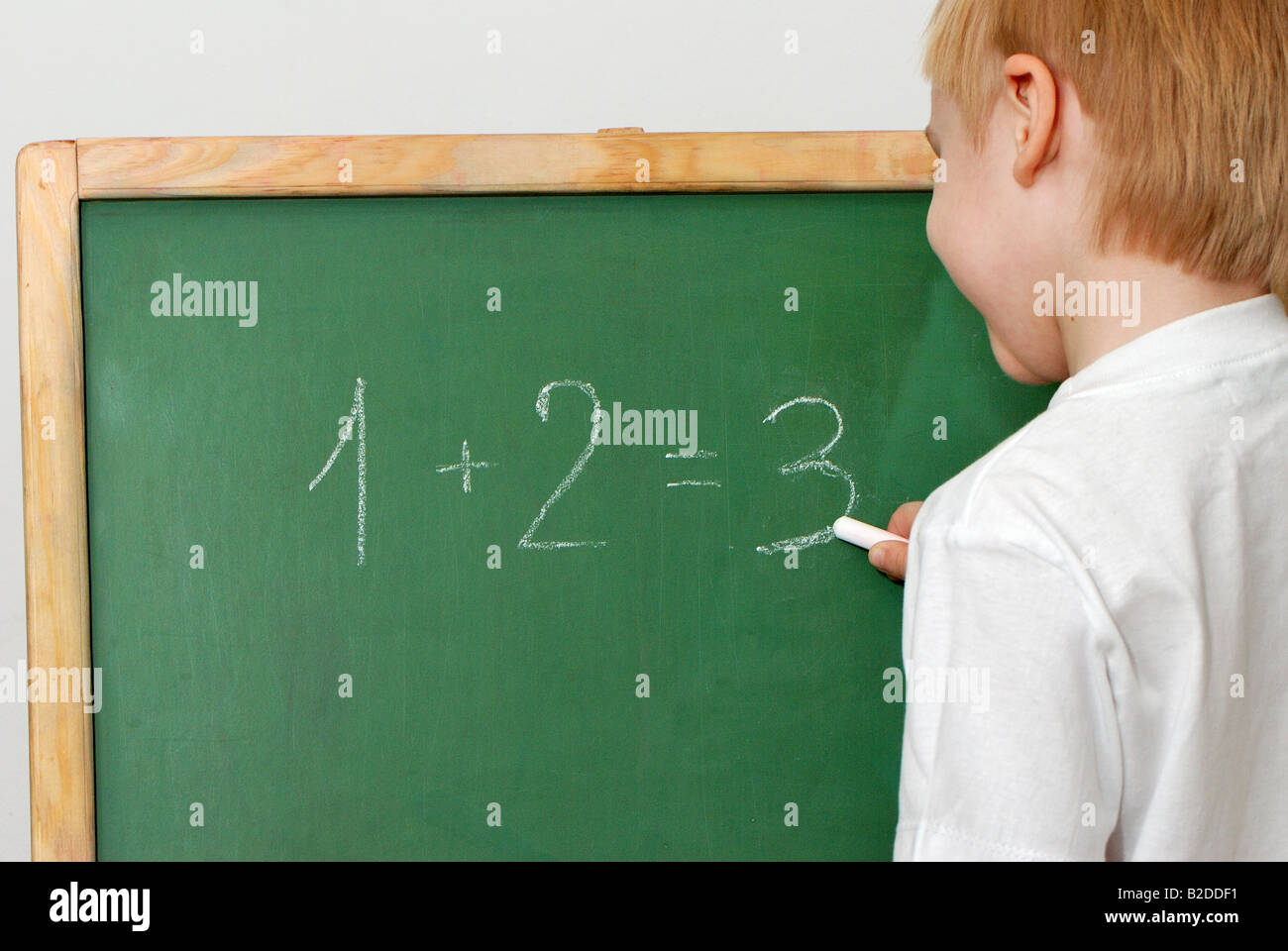Il bambino con un gesso in prossimità di un bordo risolve attività matematiche Foto Stock