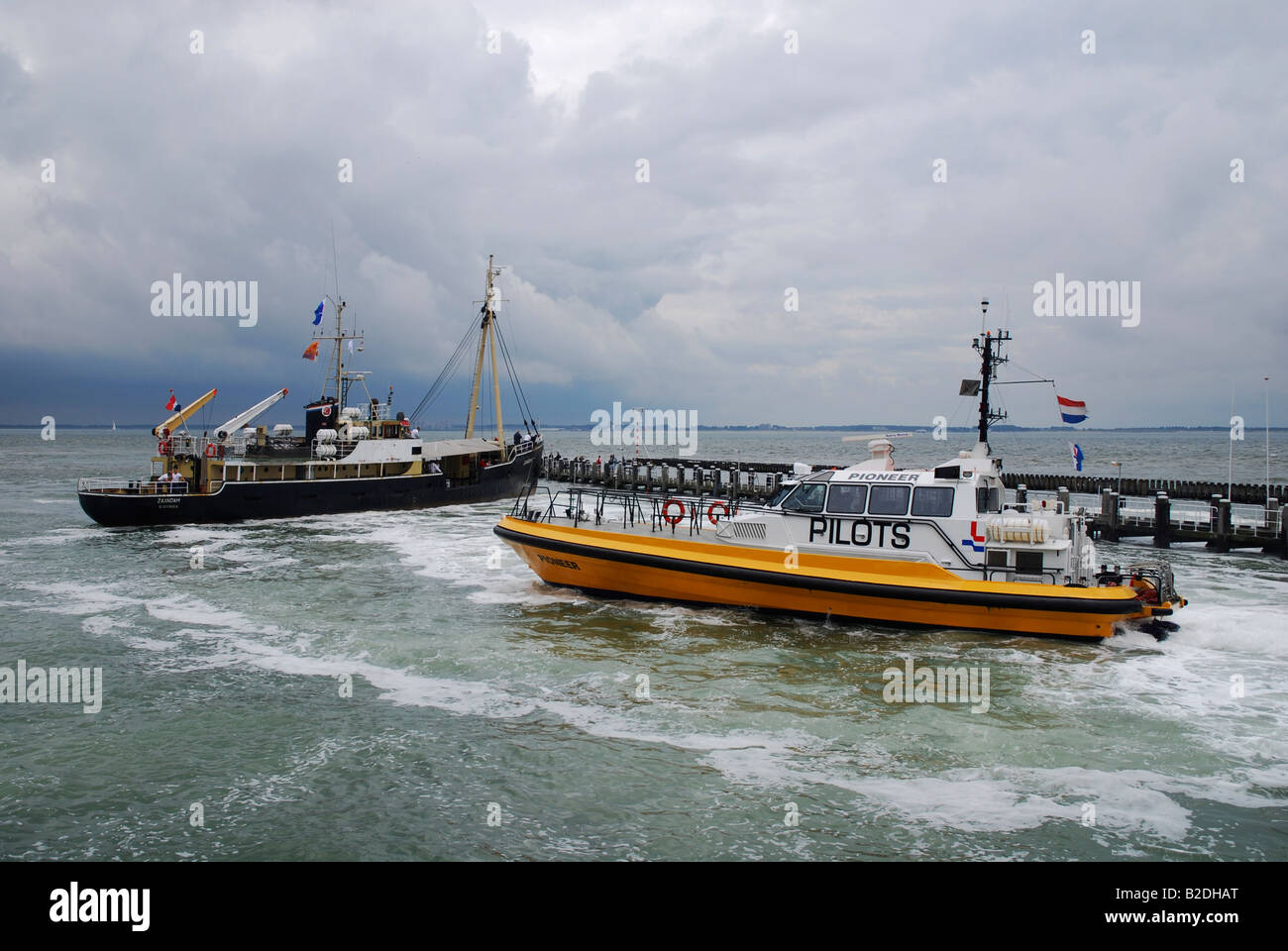 Giallo barca pilota assistere il trasporto merci nave con attracco Vlissingen Paesi Bassi Europa Foto Stock