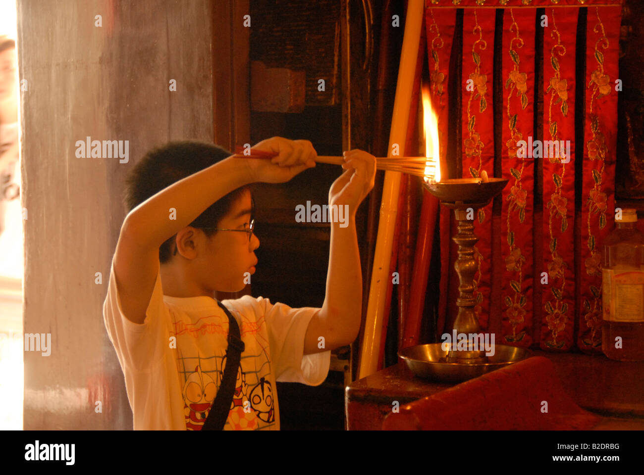 Bambino accendendo candele, Tempio Man Mo, Hollywood Road, Hong Kong, Cina Foto Stock