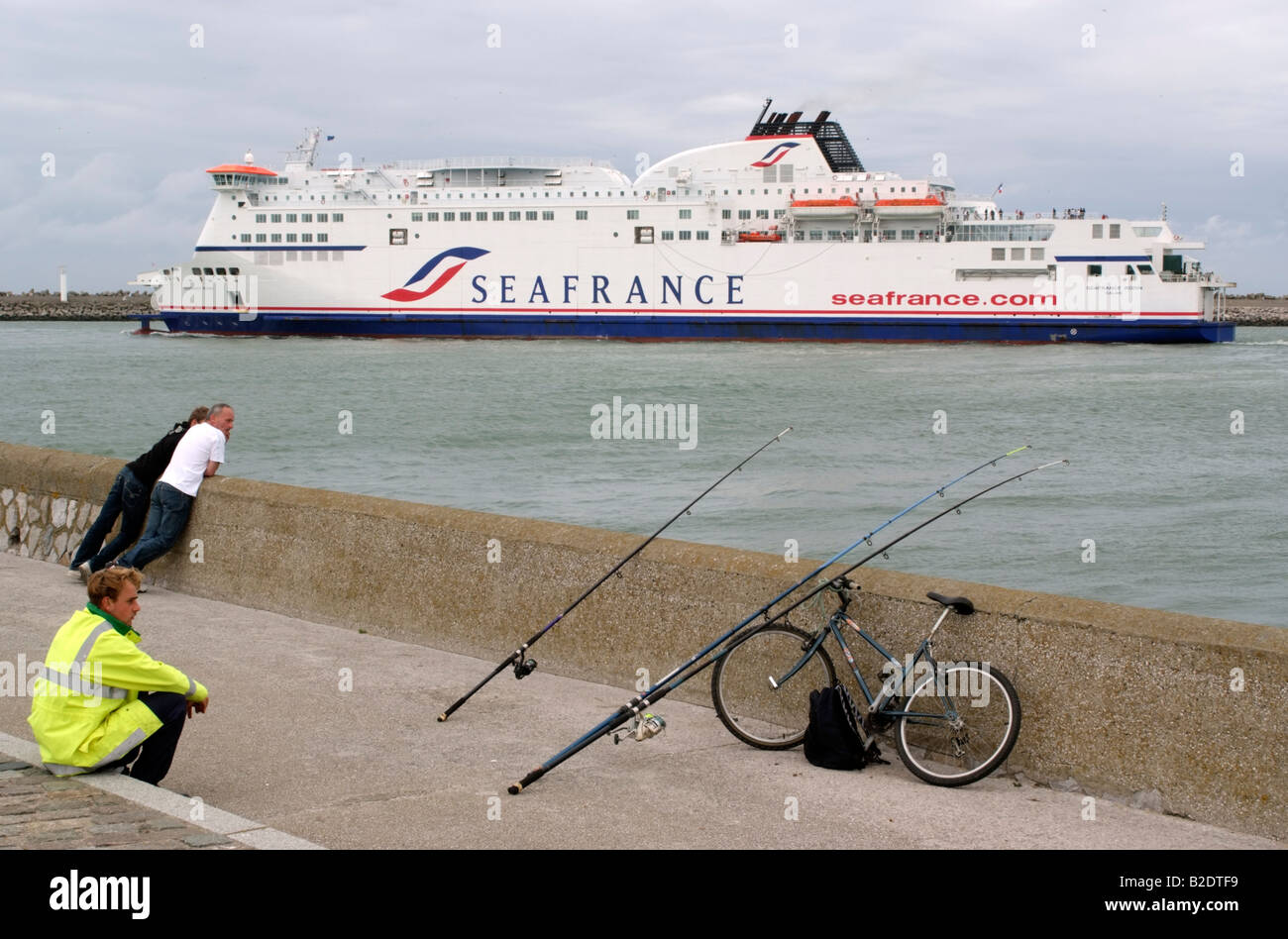 Porto di Calais Francia Europa uomini la pesca in un noioso nuvoloso giorno Foto Stock