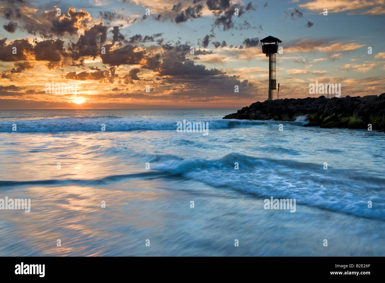 Groyne e surf della torre di vedetta al tramonto. City Beach, Perth, Western Australia Foto Stock