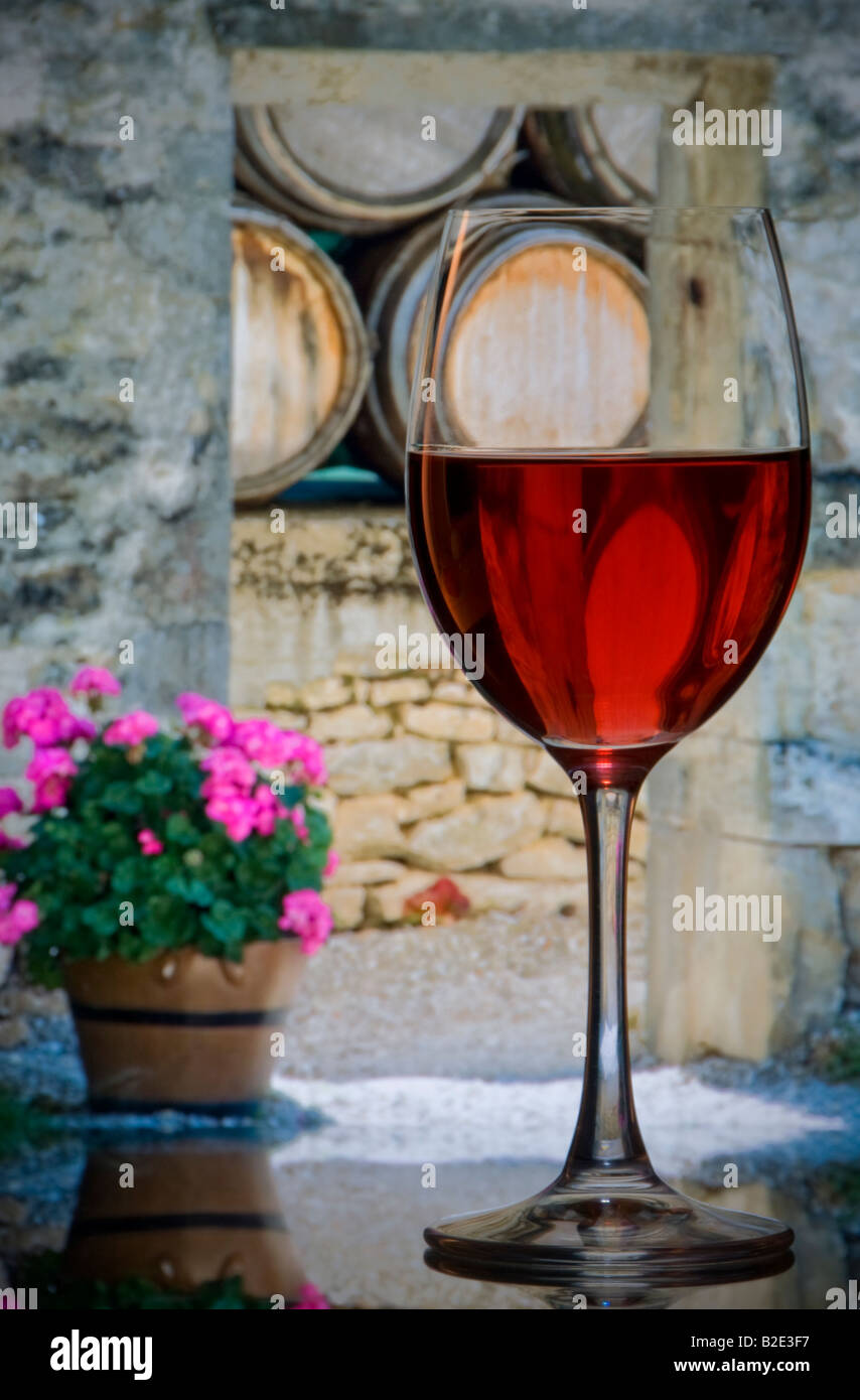 Il vino francese Cantina degustazione vino rosato di vetro con una rustica cantina francese arch e botti in background Francia Foto Stock