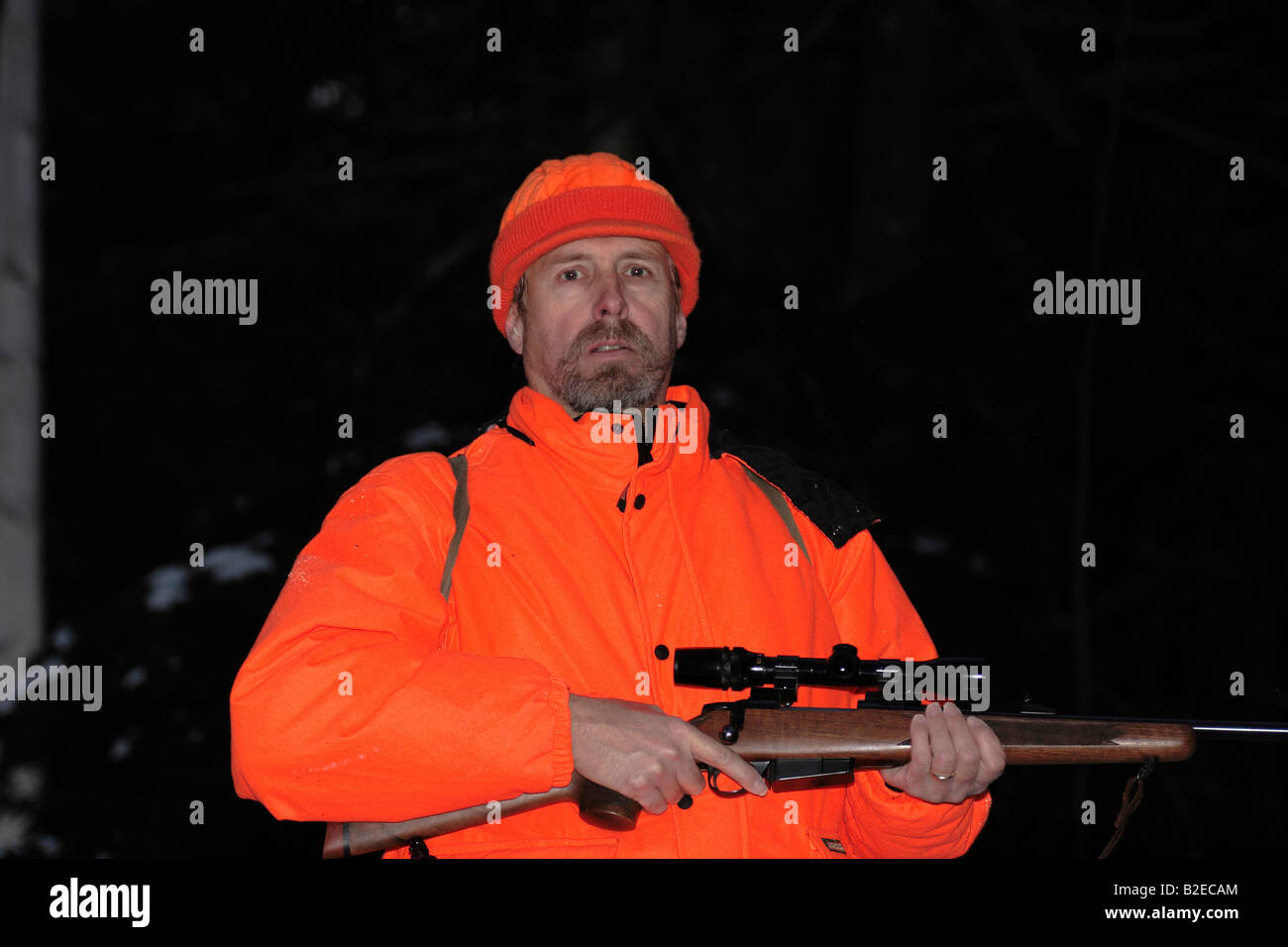 Un cacciatore dei cervi in hunter orange abbigliamento tenendo un alto powered rifle Foto Stock