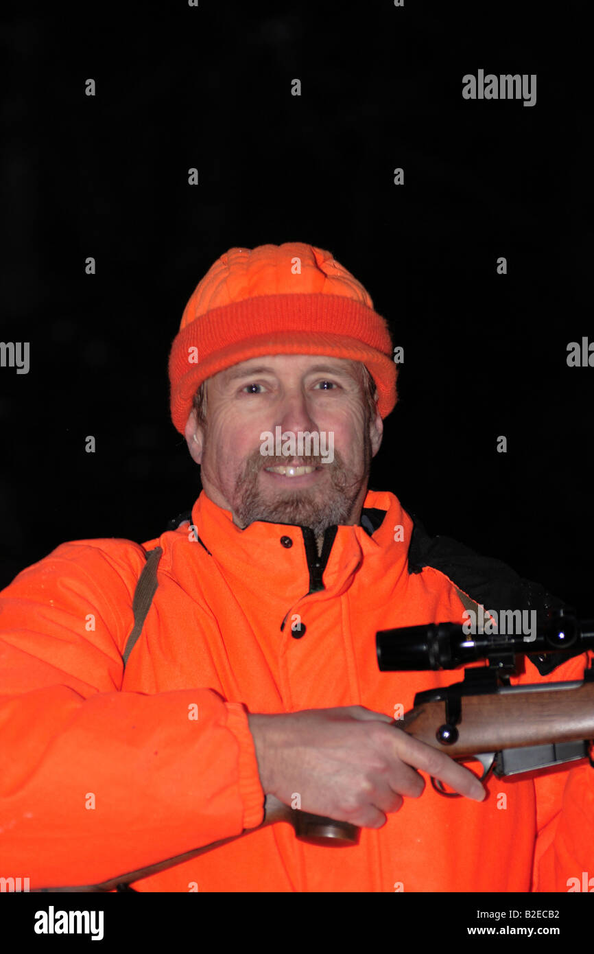 Un cacciatore dei cervi in hunter orange abbigliamento tenendo un alto powered rifle Foto Stock