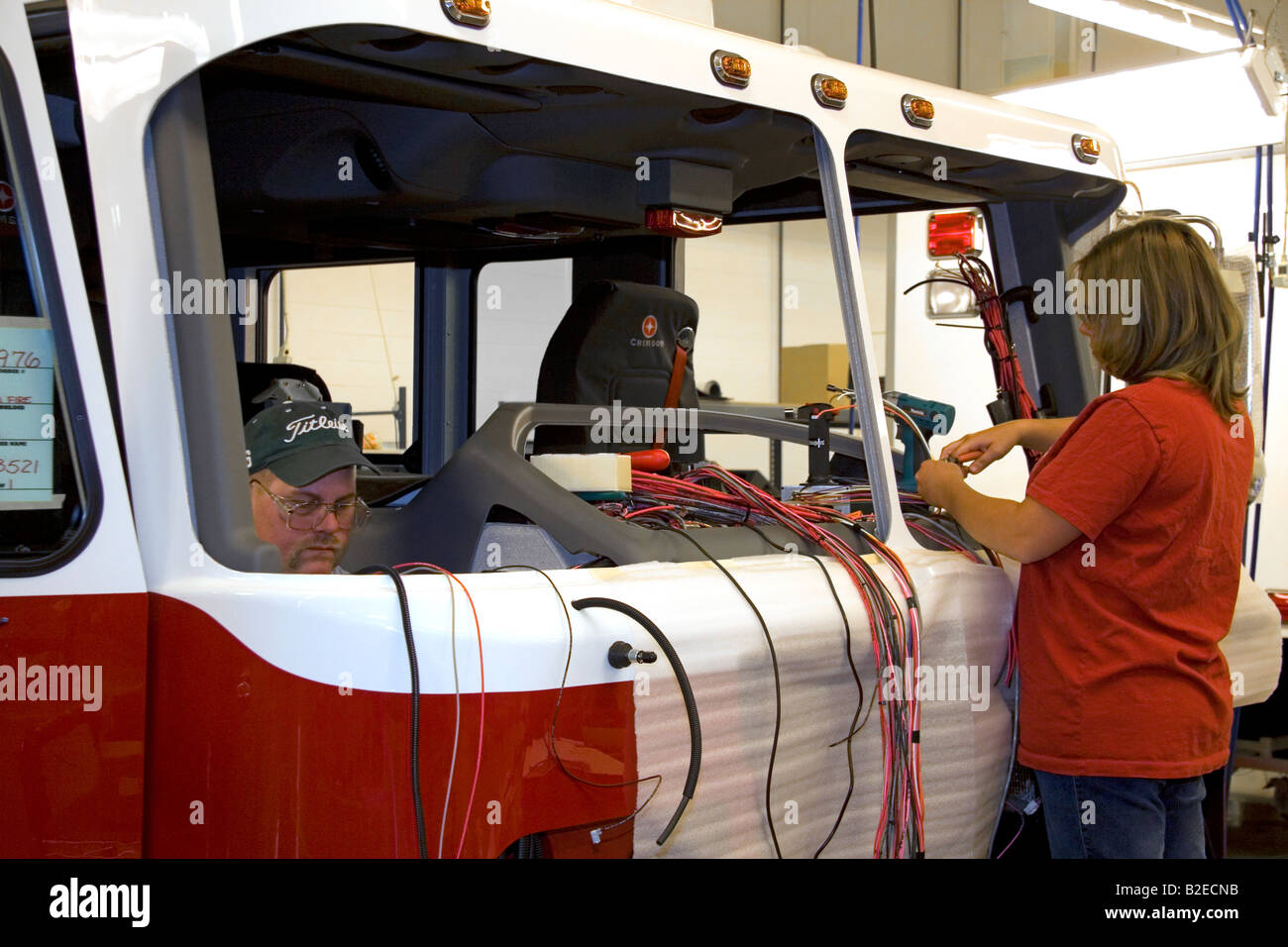 Lavoratori installare il cablaggio in un fabbricato di recente incendio il telaio del carrello a Spartan Motors a Charlotte nel Michigan Foto Stock