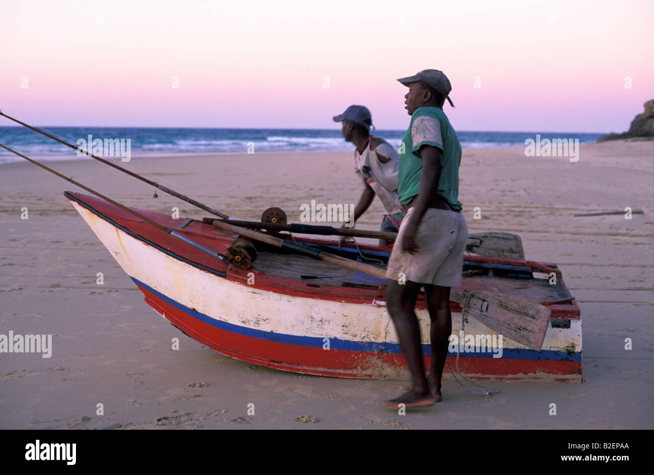 Due i pescatori locali con la loro barca sulla spiaggia all'alba Foto Stock