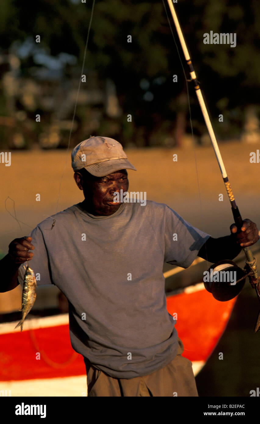 Fisherman tenendo in mano un piccolo pesce truccate con ganci e pronto per essere utilizzato come esca di deriva Foto Stock