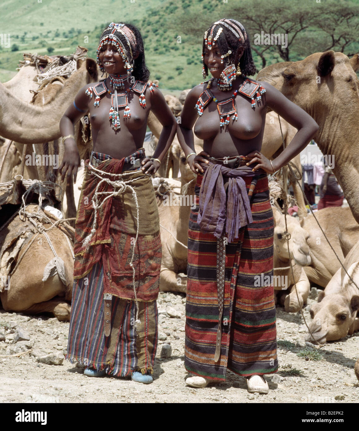Due giovani ragazze Afar stare accanto a loro cammelli al mercato Senbete. Sono arredate, acconciature e gioielli di perline. Foto Stock