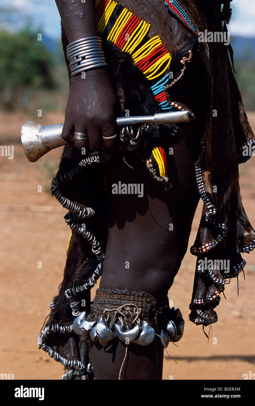 Un Hamar donna indossa una moltitudine di perline gonna in pelle e campane attorno a lei le gambe così come portante un corno di stagno. Foto Stock