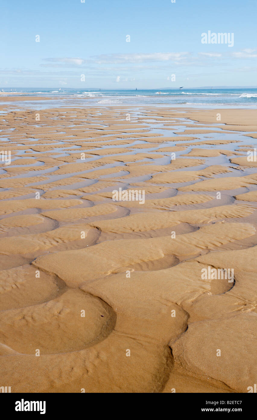 Mezza luna patterns scolpito su una spiaggia idilliaca sulla costa del Mozambico. Dhow a vela in lontananza Foto Stock
