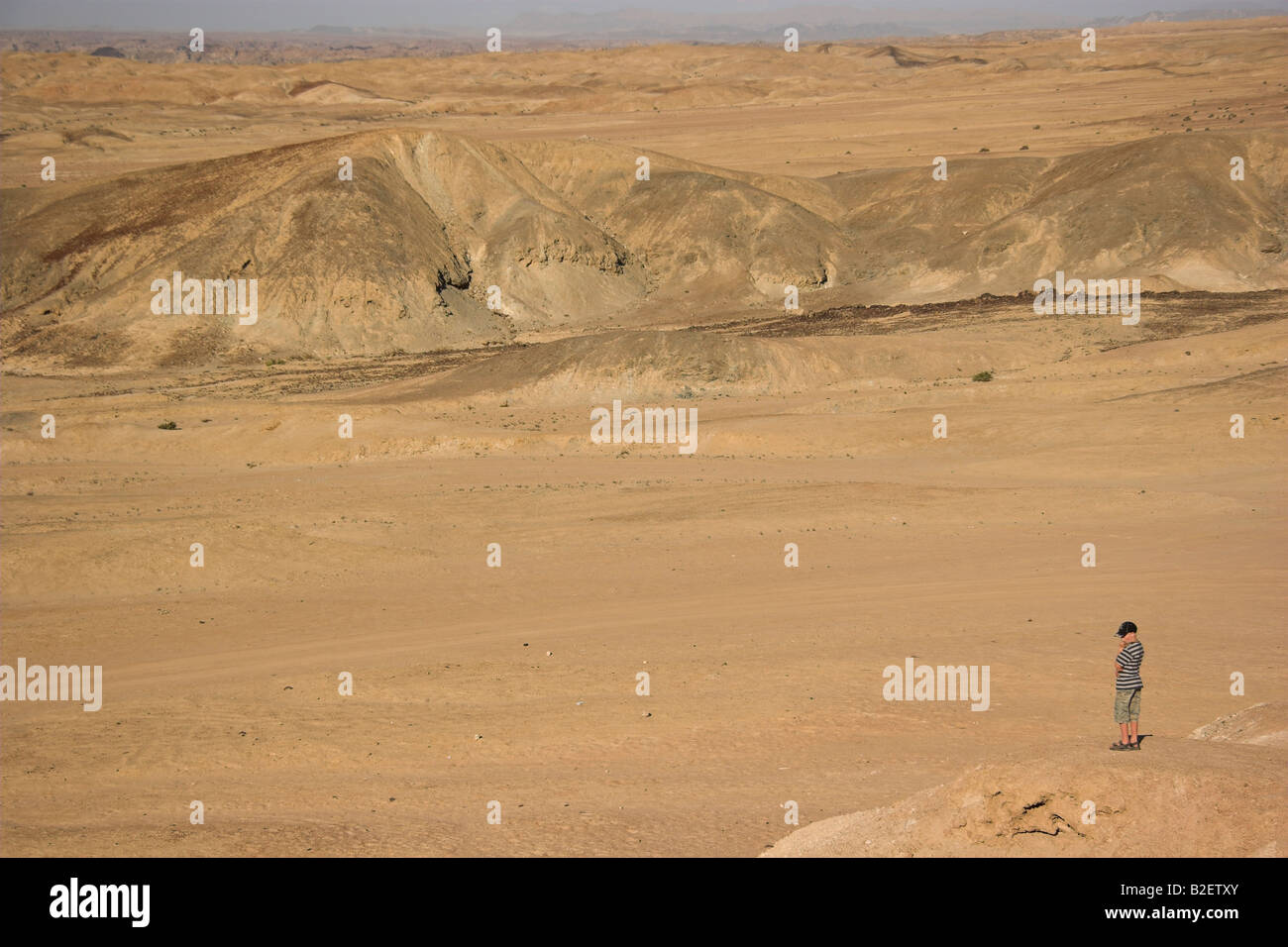 Una solitaria figura guardando fuori in un arido deserto montagna paesaggio Foto Stock