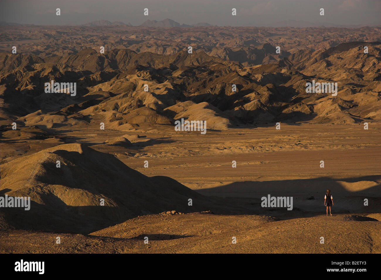 Una solitaria figura guardando fuori in un montagnoso deserto arido paesaggio Foto Stock