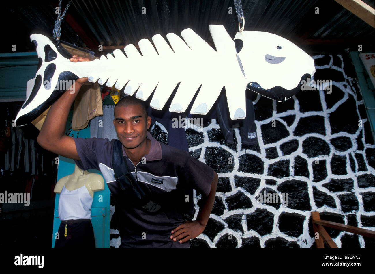 Uomo locale con legno intagliato pesce davanti al suo negozio di artigianato Foto Stock