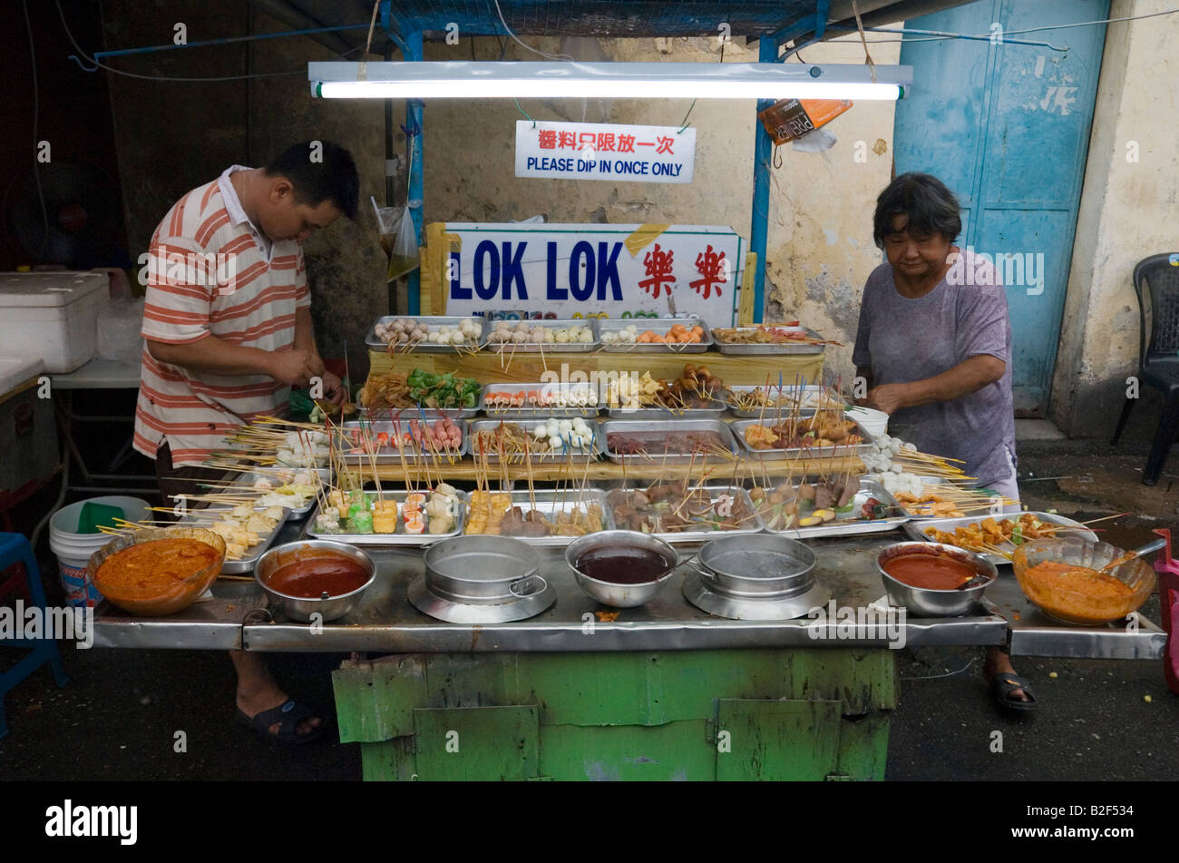 Malaysian venditore ambulante preparare snack su bastoni in corrispondenza di un lato della strada di stallo alimentare in Chinatown, Georgetown, Penang, Malaysia Foto Stock