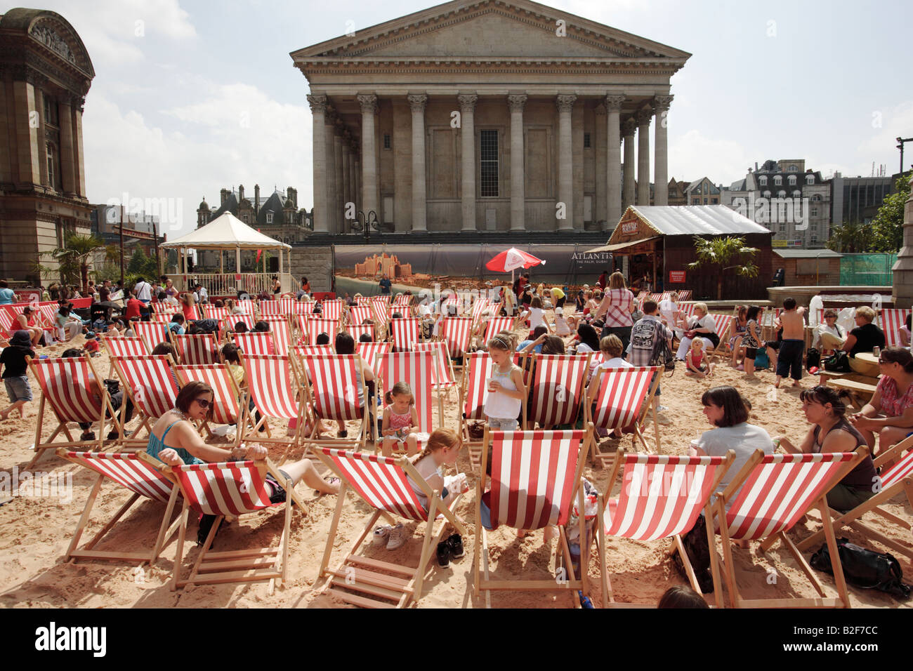 I visitatori di Birmingham's Chamberlain Square nel Regno Unito seduti in sedie a sdraio su una spiaggia artificiale. Foto Stock