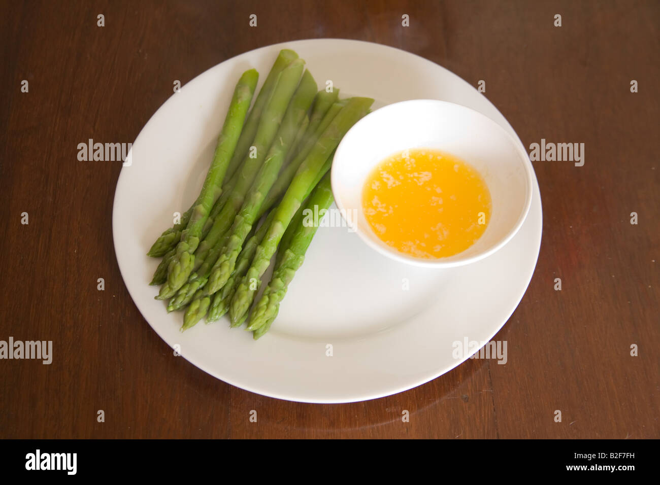 I germogli di asparagi e il burro dip su una porcellana bianca piastra. Foto Stock