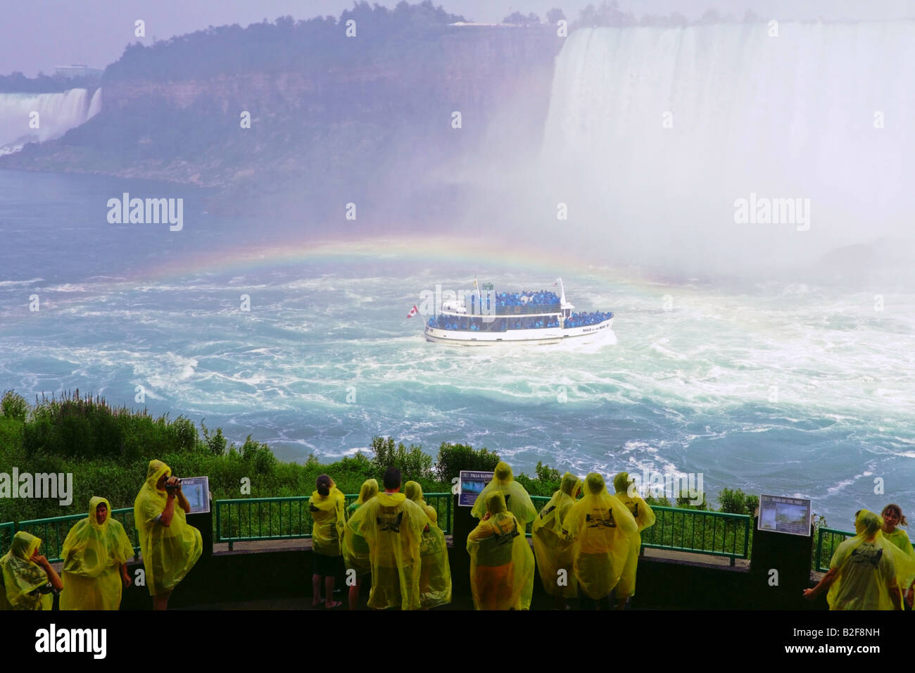 I turisti nella parte inferiore della piattaforma di osservazione del Viaggio Dietro le Cascate guardando le Cascate del Niagara con arcobaleno e la Domestica della Foschia Foto Stock