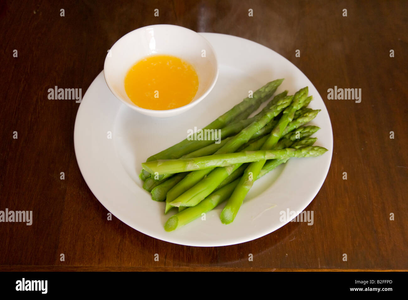 I germogli di asparagi e il burro dip su una porcellana bianca piastra. Foto Stock