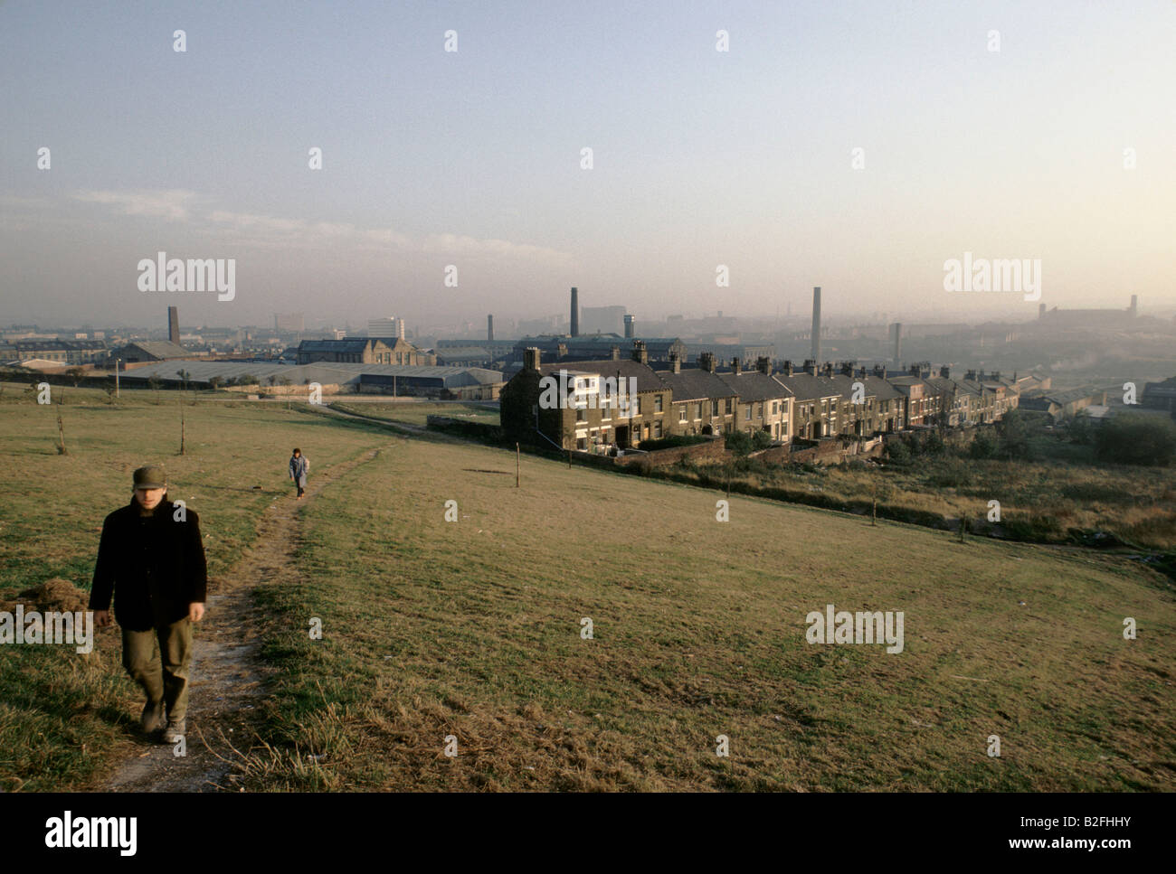 Uomo che cammina fino alla cima di una collina con una vista sulla città di Bradford Foto Stock