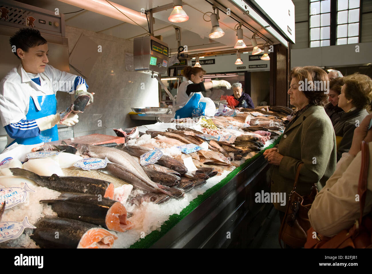 Spagna Salamanca uomini e donne shop al fish monger al mercato coperto venditore mostra il pesce fresco per il cliente Foto Stock