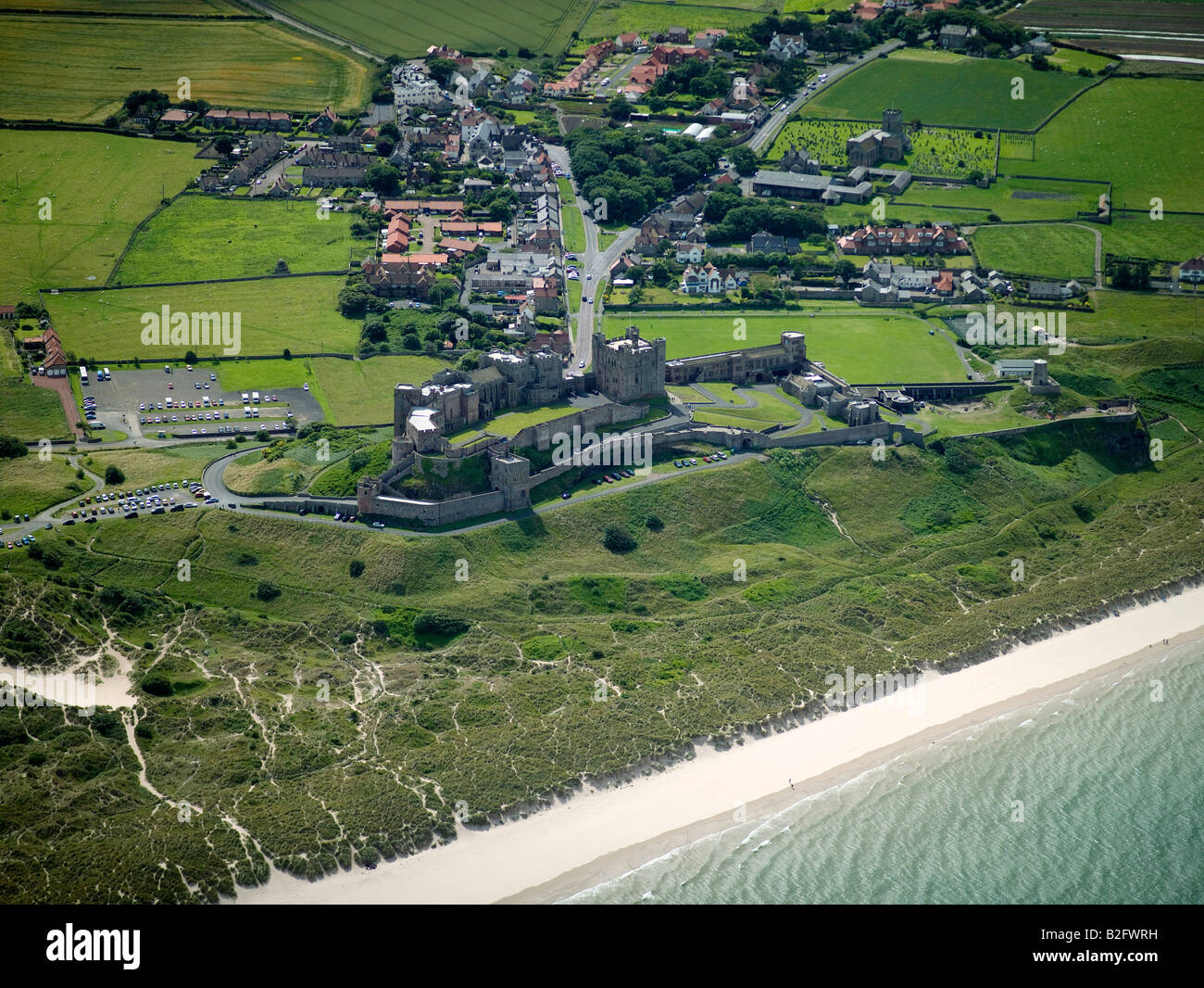Il castello di Bamburgh e villaggio sulla costa Northumbrian, Northumberland, Nord Est Inghilterra Foto Stock