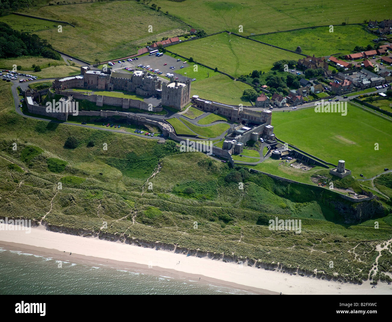 Il castello di Bamburgh e villaggio sulla costa Northumbrian, Northumberland, Nord Est Inghilterra Foto Stock