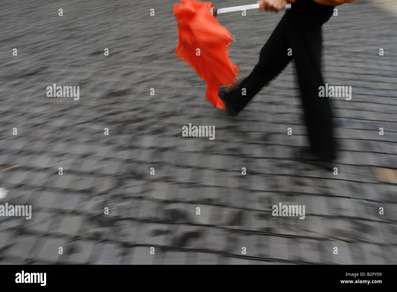 Persona che porta con sé coloratissimo ombrello chiuso in città Foto Stock