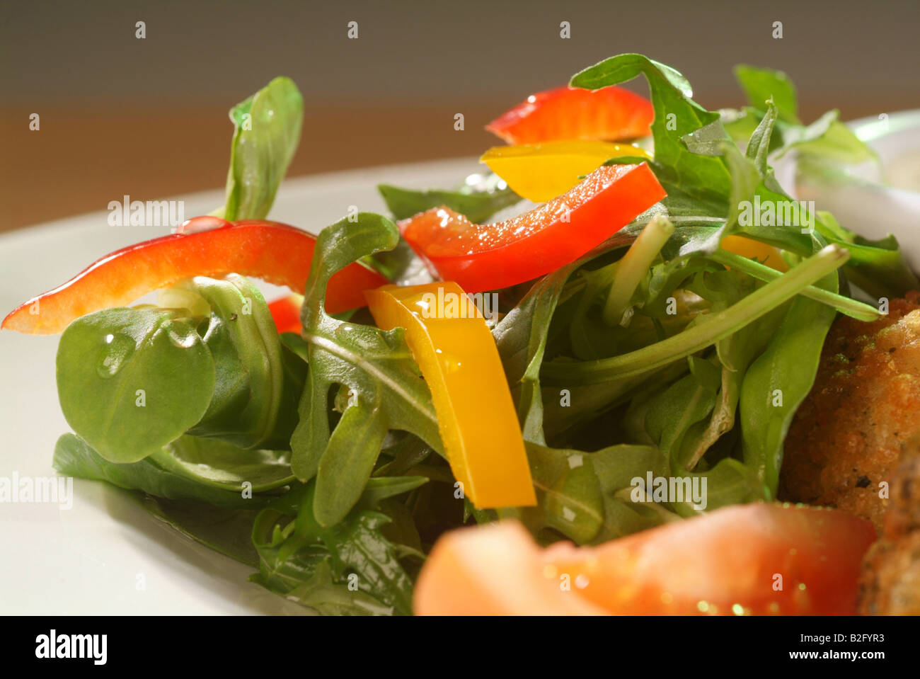 Pomodori, peperoni rossi e gialli sulla parte superiore della lattuga a razzo Foto Stock