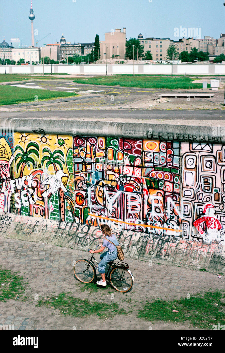 Una ragazza cavalca la sua bicicletta lungo il muro di Berlino 1986 Foto Stock