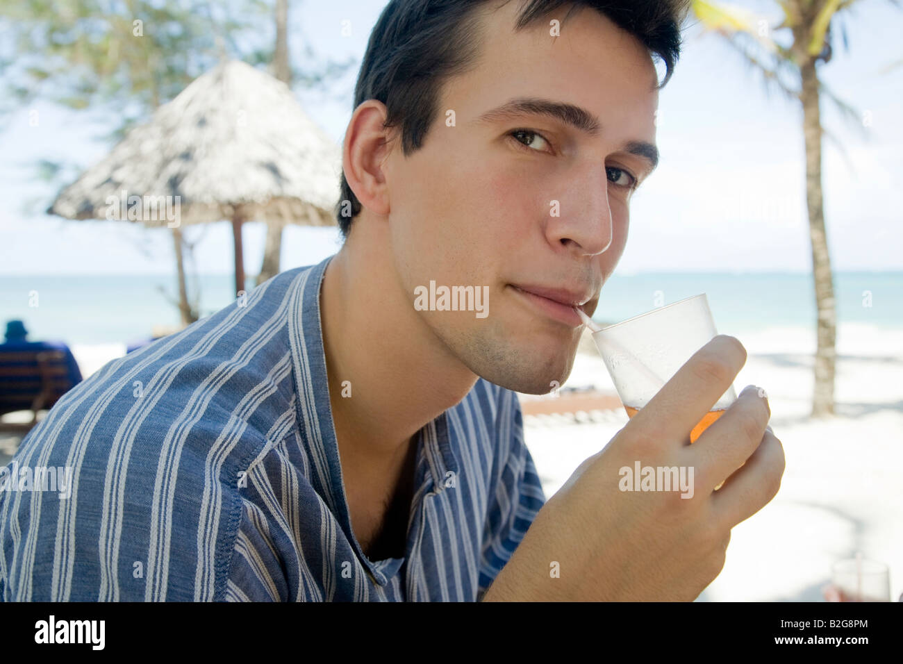 Giovane uomo modello Sigaretta fumare ciggy Junger Mann trinkt einen Cocktail am Hotelstrand Foto Stock