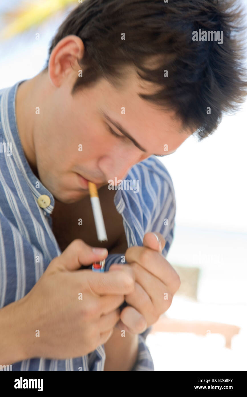 Giovane uomo modello Sigaretta fumare ciggy Junger Mann zündet sich bei Wind eine Zigarrette un Foto Stock