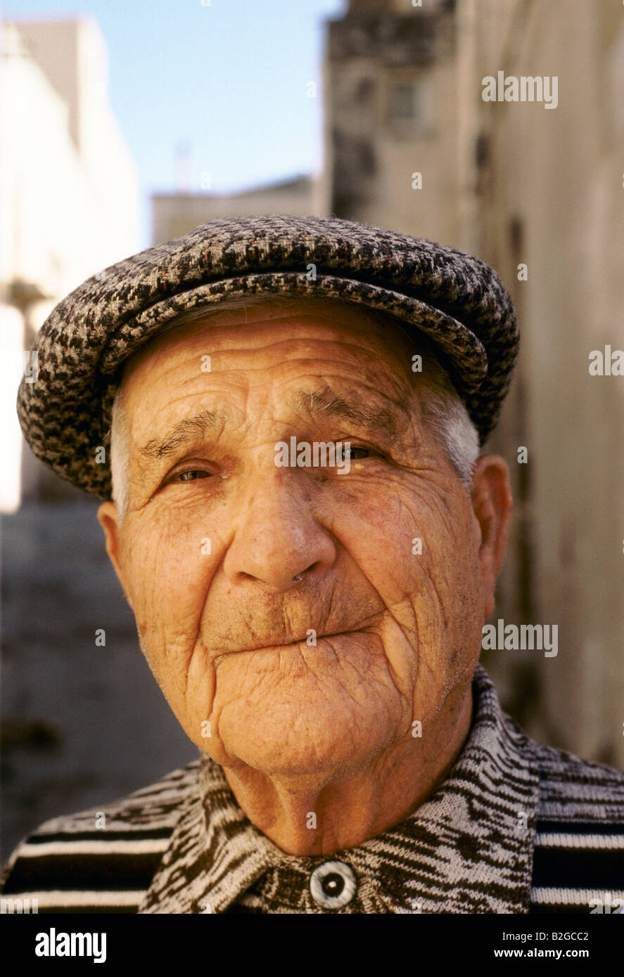Un anziano uomo siciliano indossa un cappello in tweed e sorrisi con le sue  labbra chiuse Foto stock - Alamy