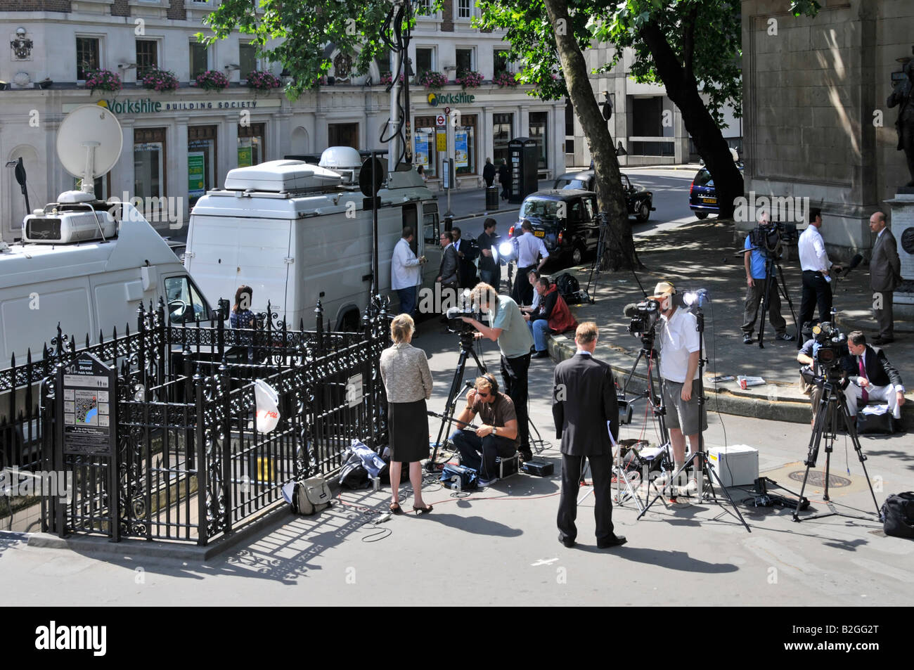 Di fronte al Royal Courts of Justice, giornalisti e giornalisti con telecamere televisive file notizie relazioni accanto al satellite van London UK Foto Stock