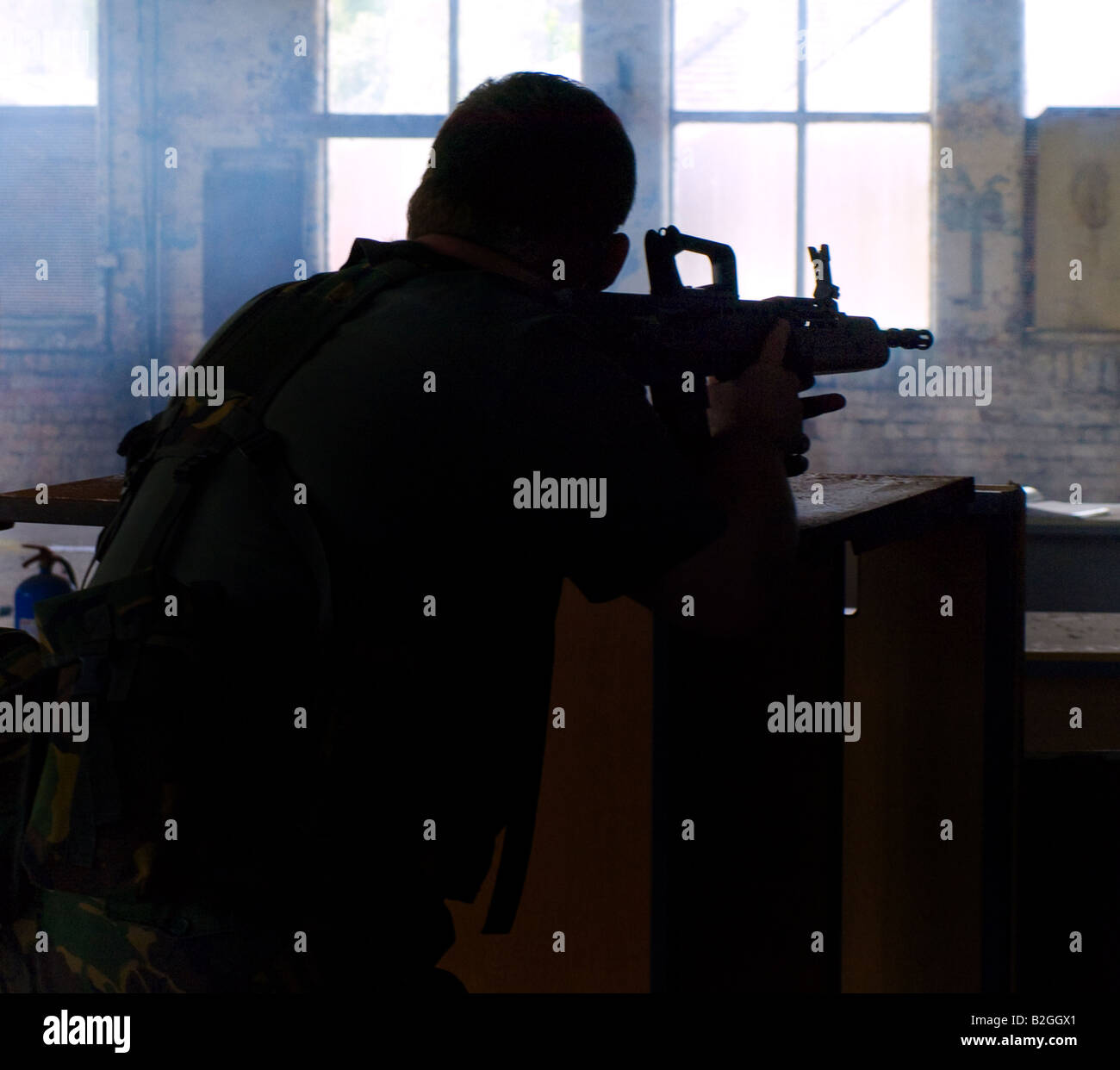 Silhouette di un soldato con il fucile di assalto per difendere il magazzino coperto Foto Stock