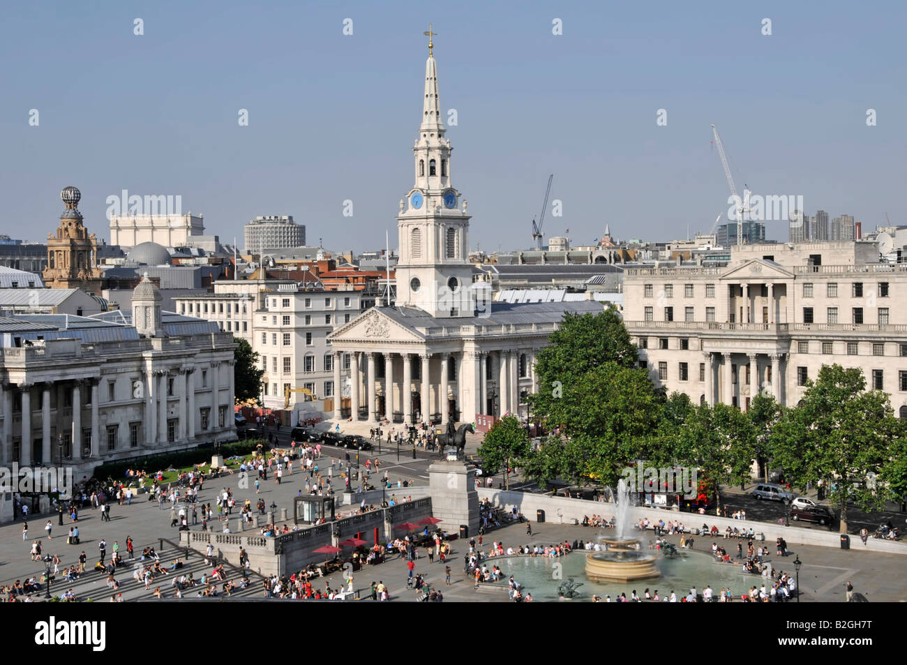 Vista dall'alto guardando verso il basso sui turisti e visitatori in Trafalgar Square include fontana & St Martins nel campo chiesa & guglia Londra Inghilterra REGNO UNITO Foto Stock