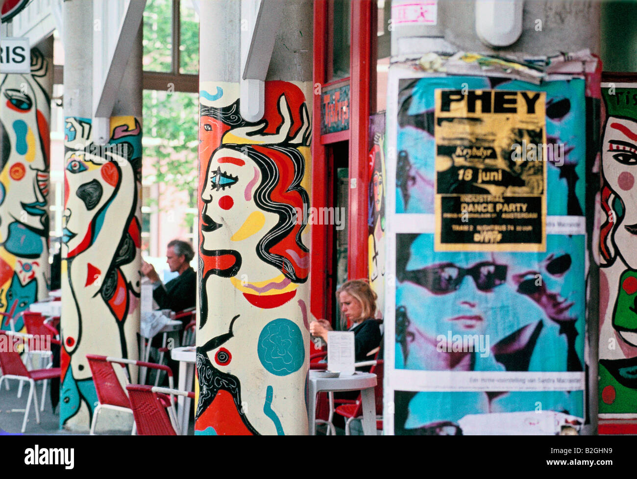Pilastri decorati con graffiti e manifesti a un cafe' all'aperto, Amsterdam Foto Stock