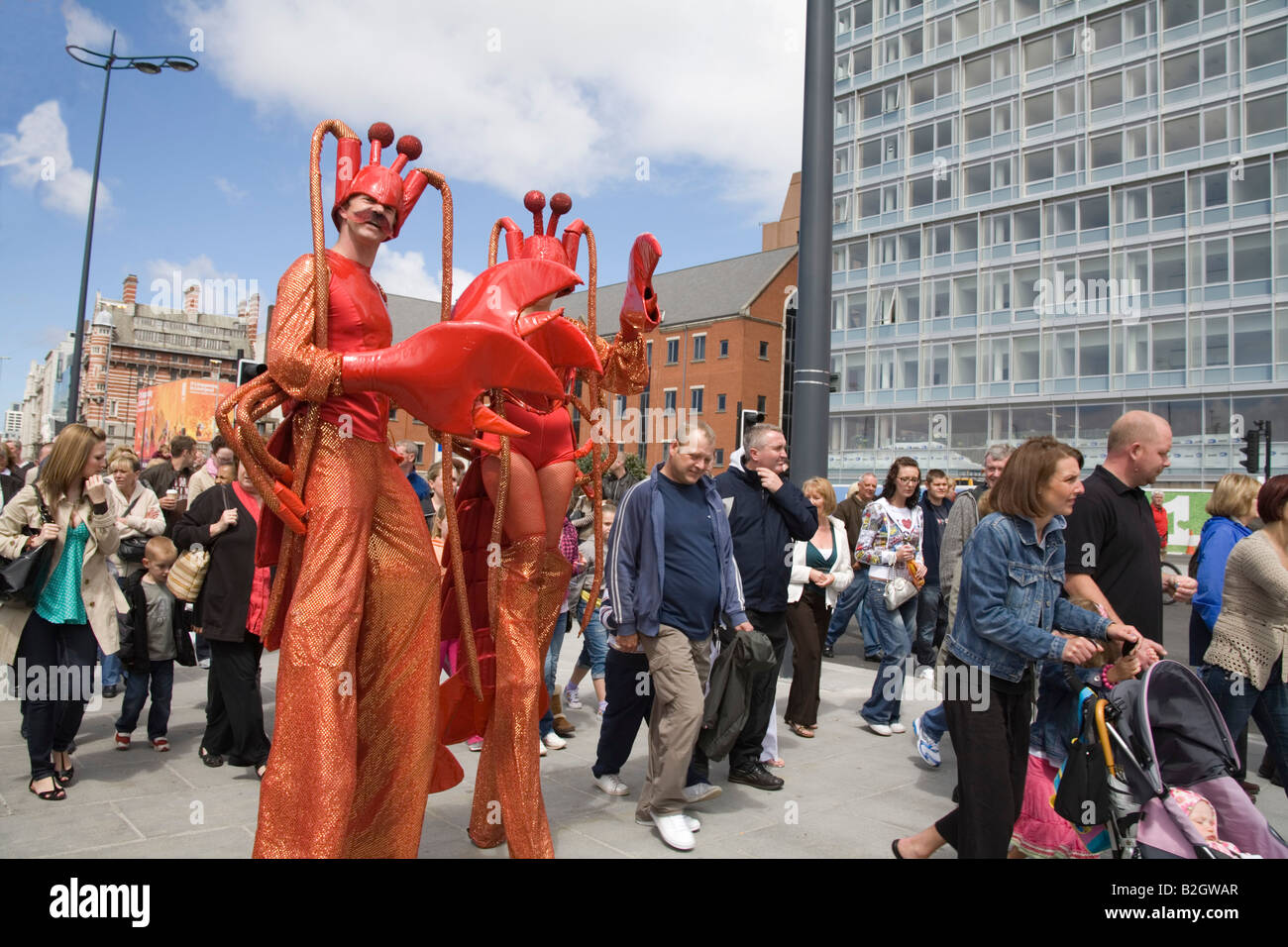 Liverpool Merseyside England Regno Unito luglio un uomo e una donna che cammina su palafitte vestiti come i granchi tra la fretta folle Foto Stock