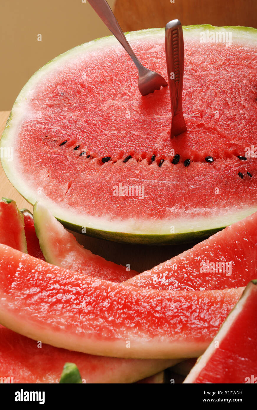 Anguria fresca con mangiato fette coltello e forchetta sono incollati a uneaten metà di melone Foto Stock