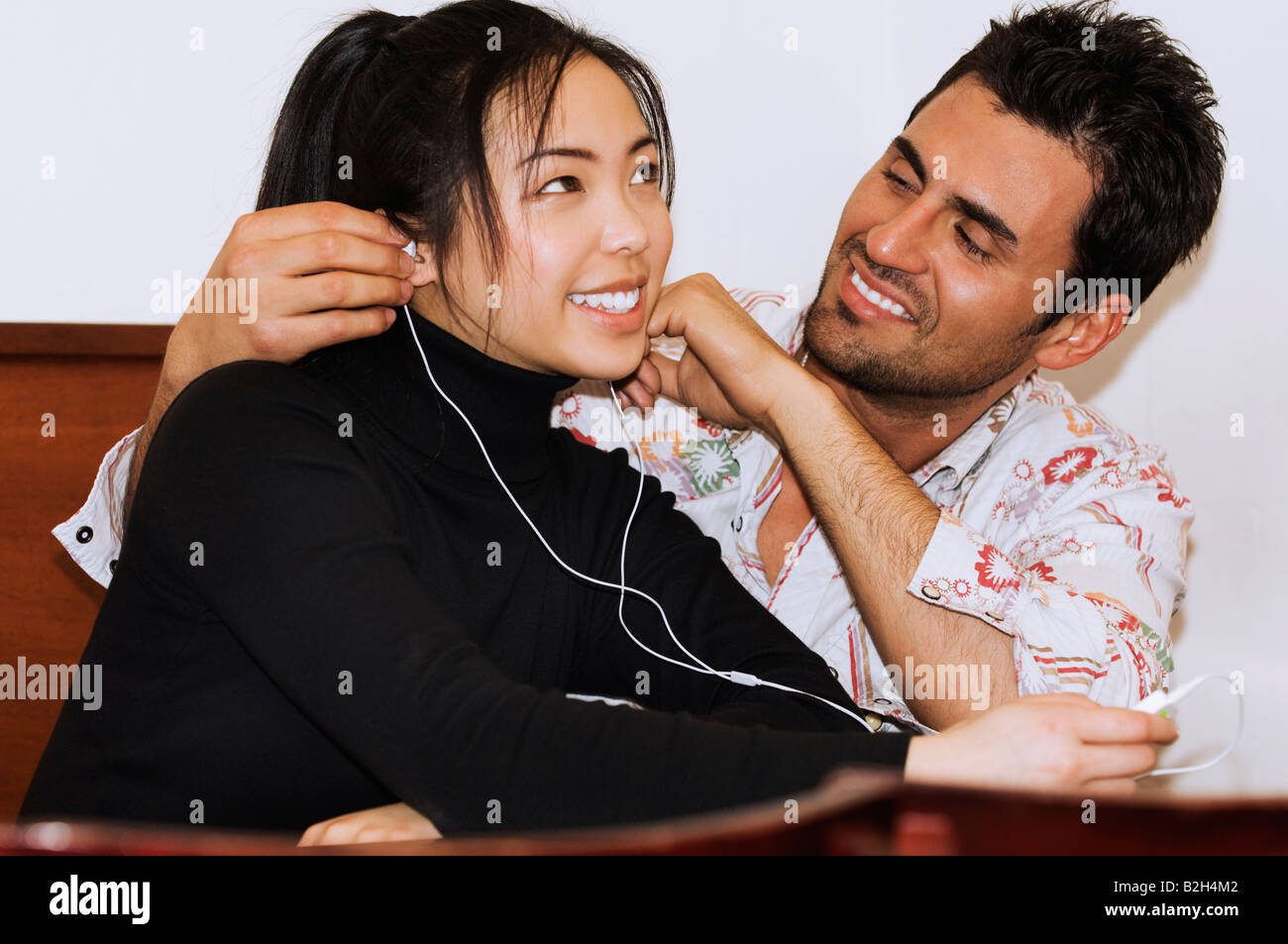 I giovani Asiatici esotici e ragazza italiano spagnolo ragazzo giovane ascoltando musica kissing Foto Stock