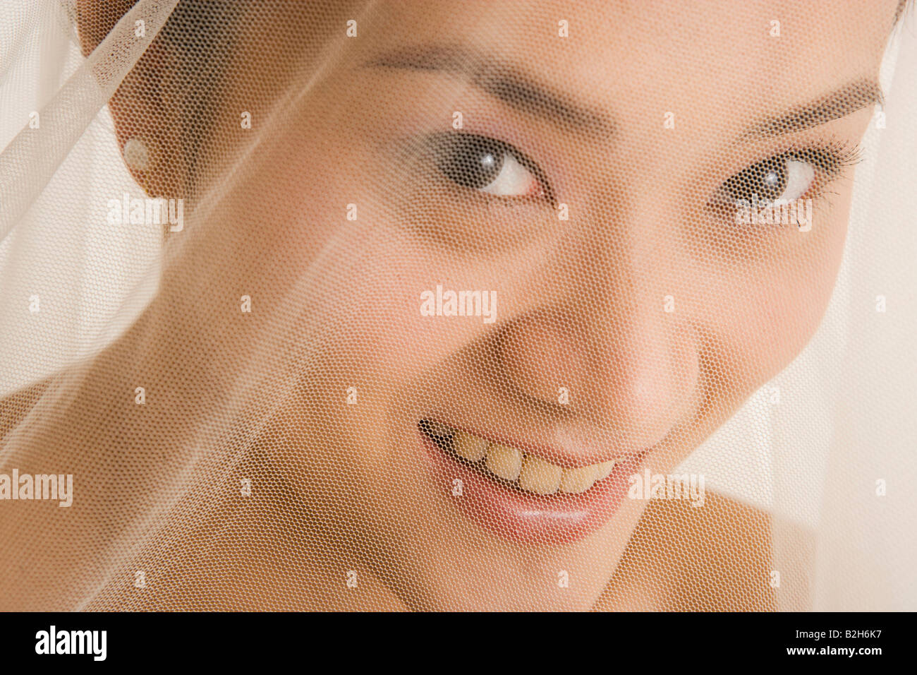 Ritratto di una sposa che copre il volto con un velo e sorridente Foto Stock