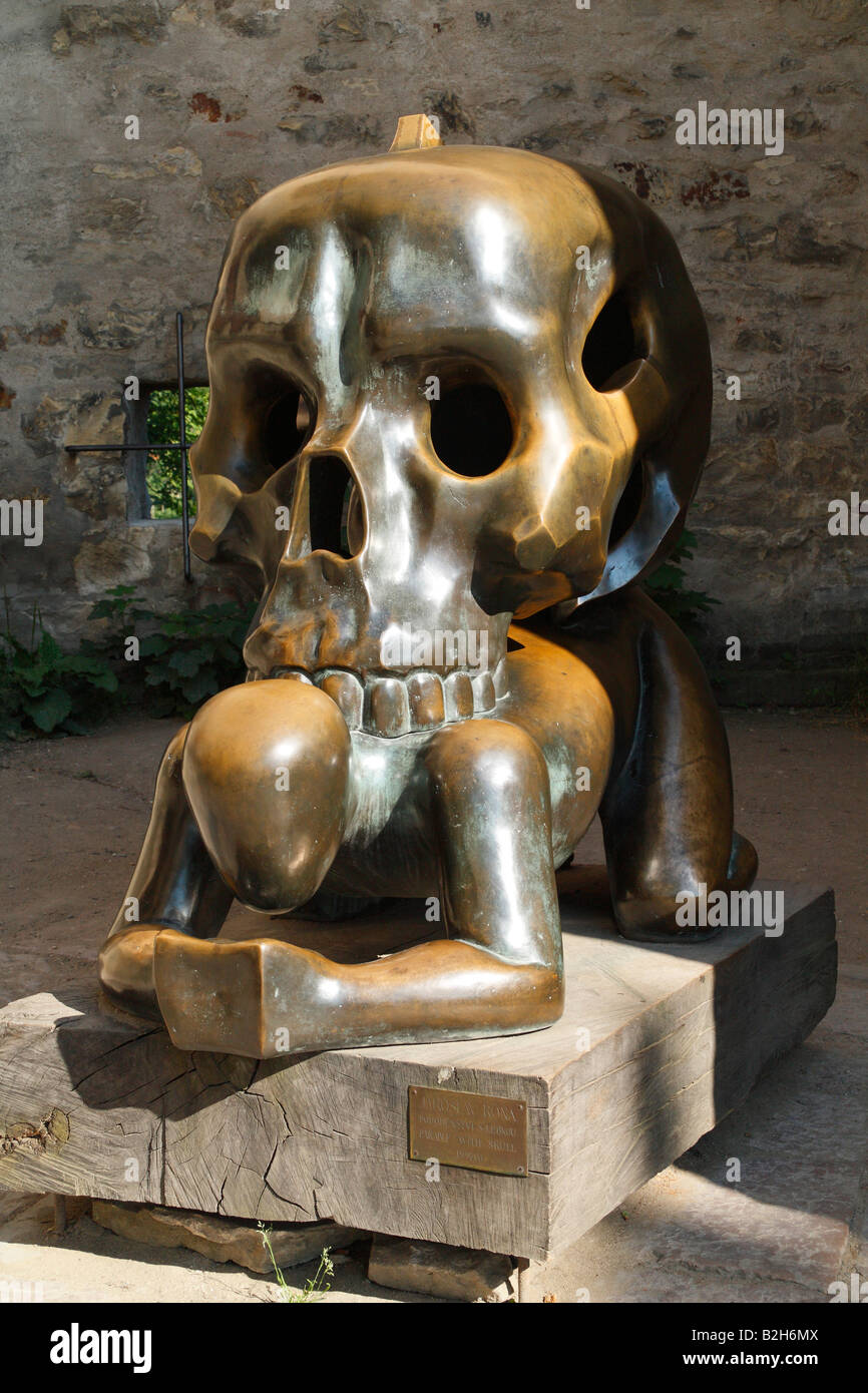 Una statua di bronzo di un uomo in piedi sulle sue ginocchia che trasportano enormi teschio sul suo retro. Foto Stock