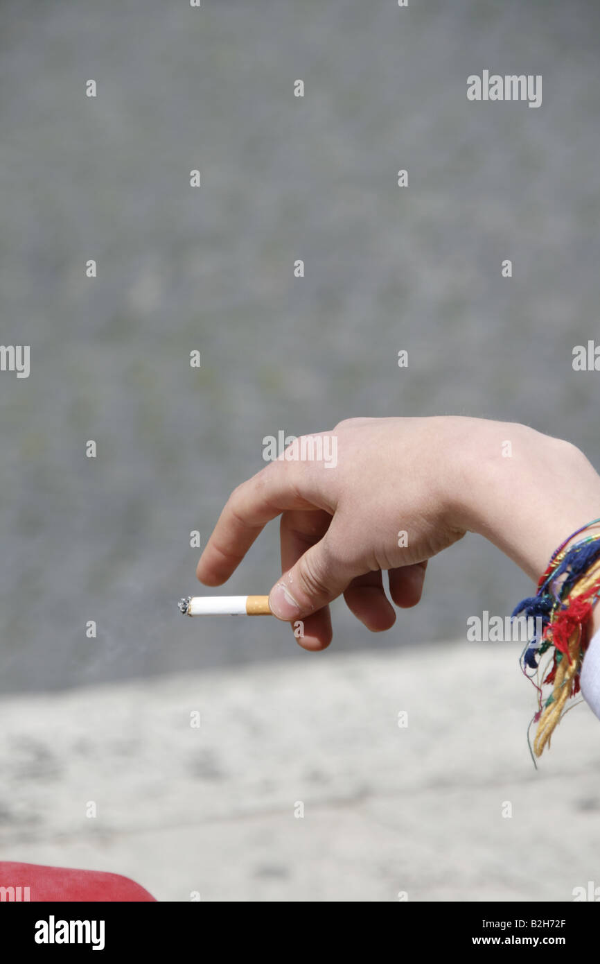 Dettaglio uomo adolescente holding sigaretta in città Foto Stock