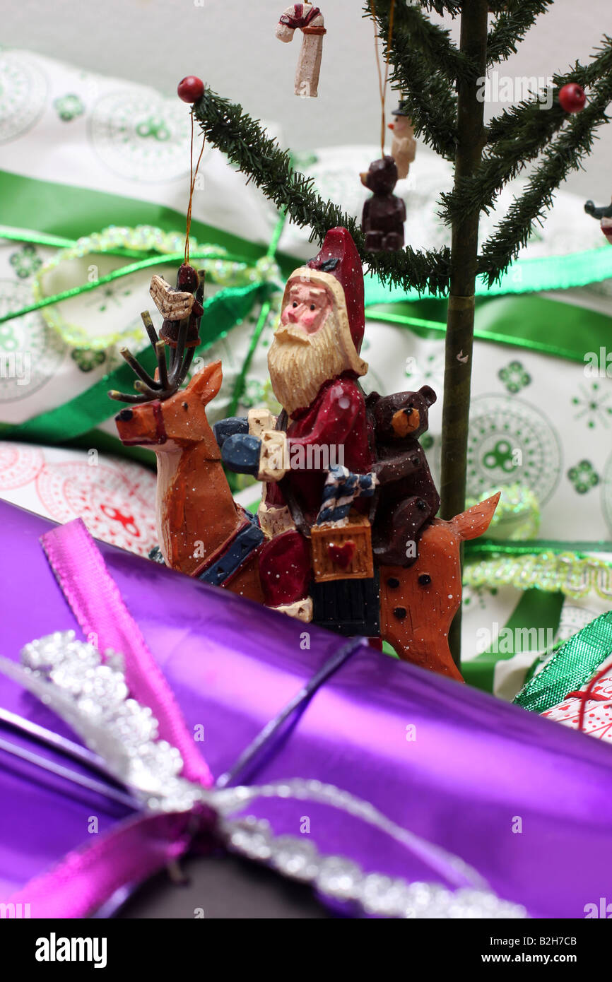 Decorazione albero di Natale tra presenta santa seduta su una renna accanto a l'albero Foto Stock