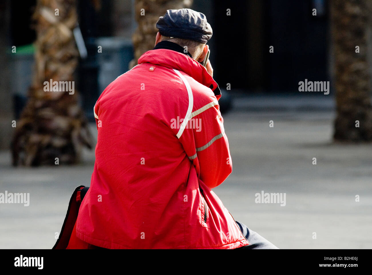 Uomo con un cappotto rosso chiamata con una cella barcelona Foto Stock